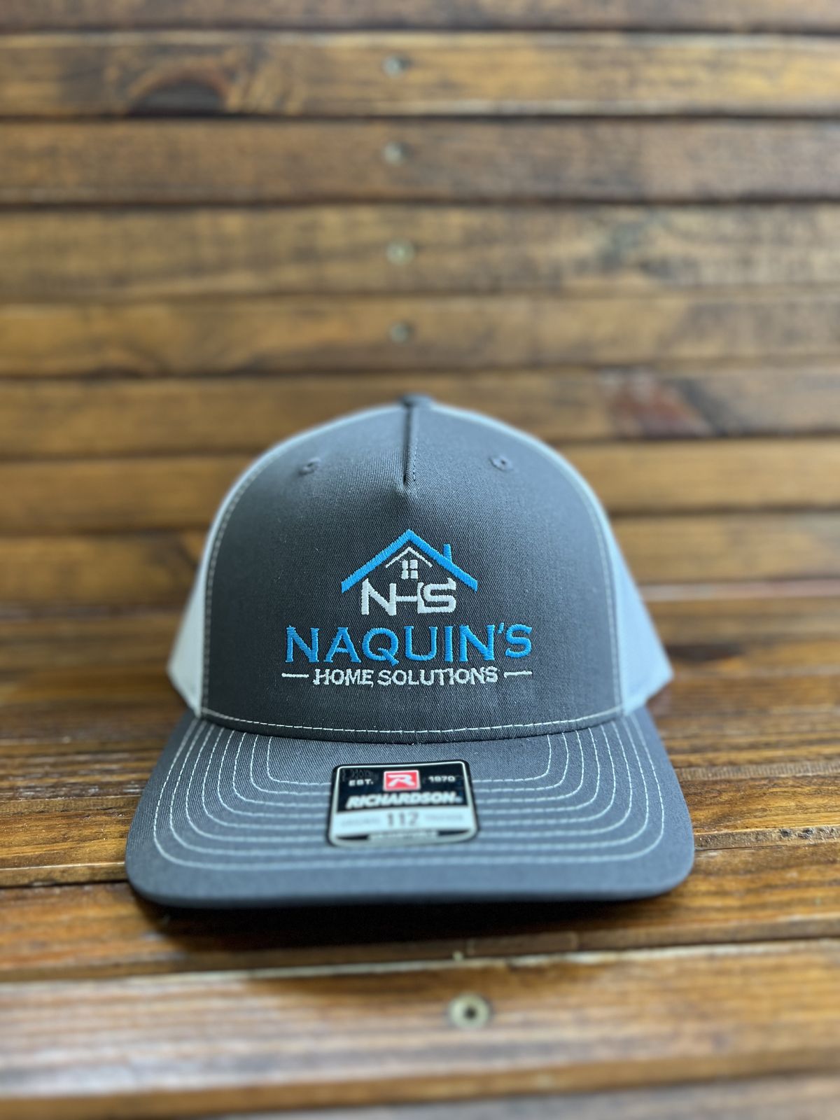 Gray Richardson 112 trucker hat with an embroidered Naquin's Home Solutions logo